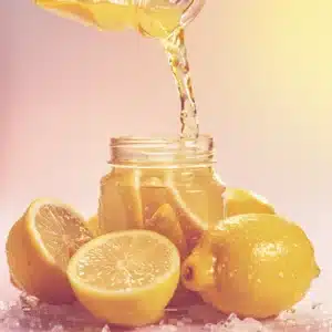 Fresh lemon juice being poured over salted lemons in a jar until fully submerged for Salt Pickled Lemons.