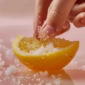 Lemon quarters being opened gently and filled with coarse salt to prepare Salt Pickled Lemons.